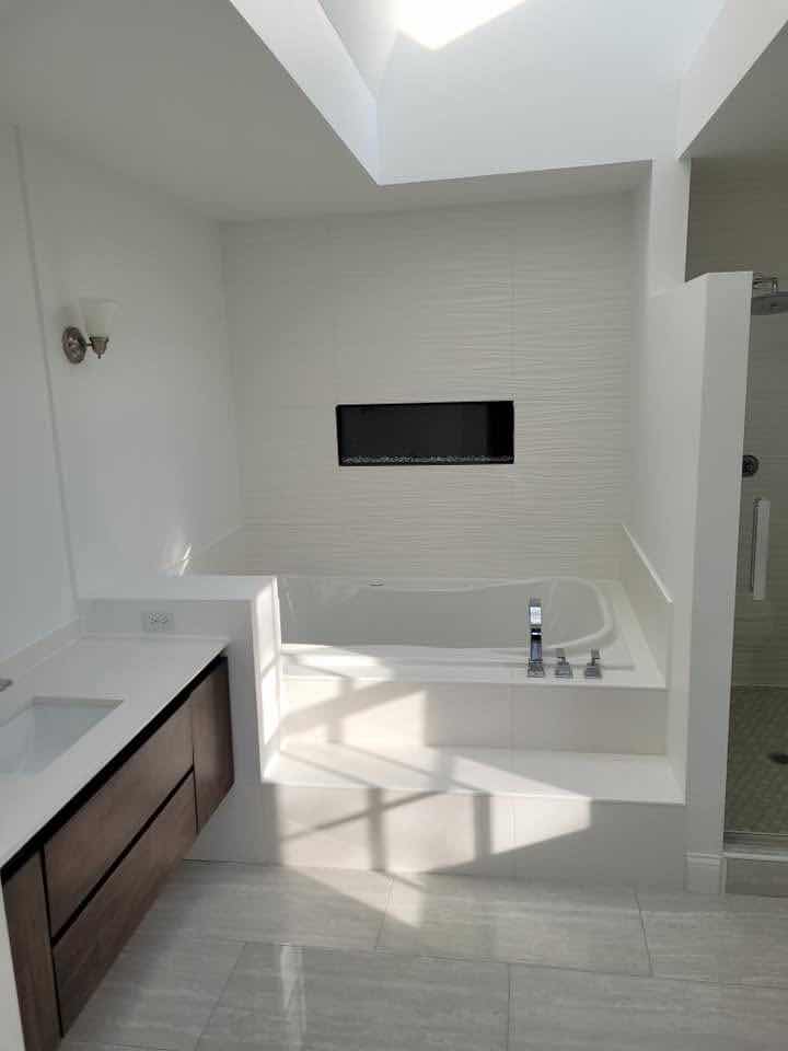 Marble-look tile floor and built-in tile fireplace niche in a master bathroom renovation by Magic Tools Contracting