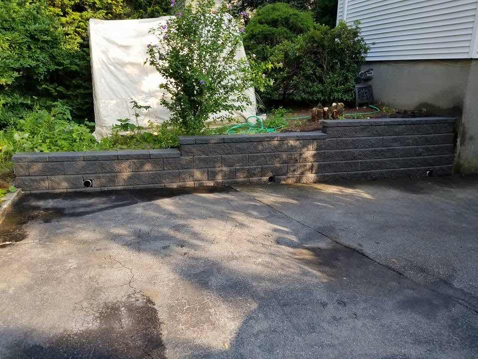 Segmental concrete block retaining wall along a driveway, built by Magic Tools Contracting