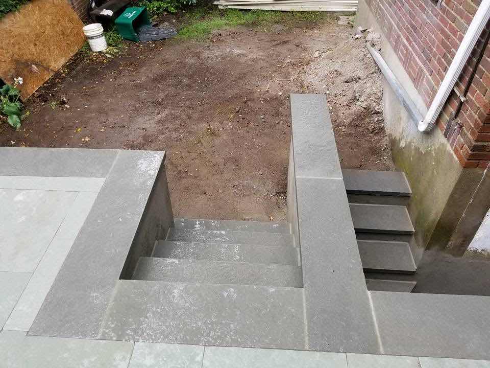 Bluestone exterior stairs leading down to a walkout basement entrance, built by Magic Tools Contracting