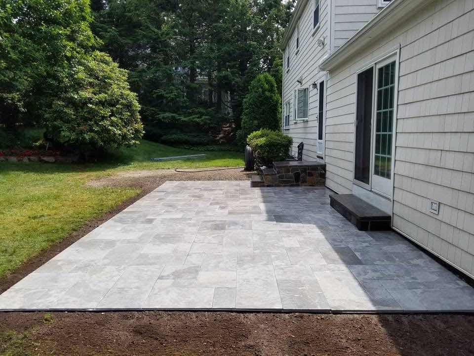 Large bluestone paver patio behind a home, installed by Magic Tools Contracting