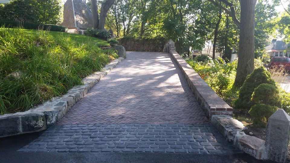 Long curved herringbone brick driveway with granite curbing, installed by Magic Tools Contracting