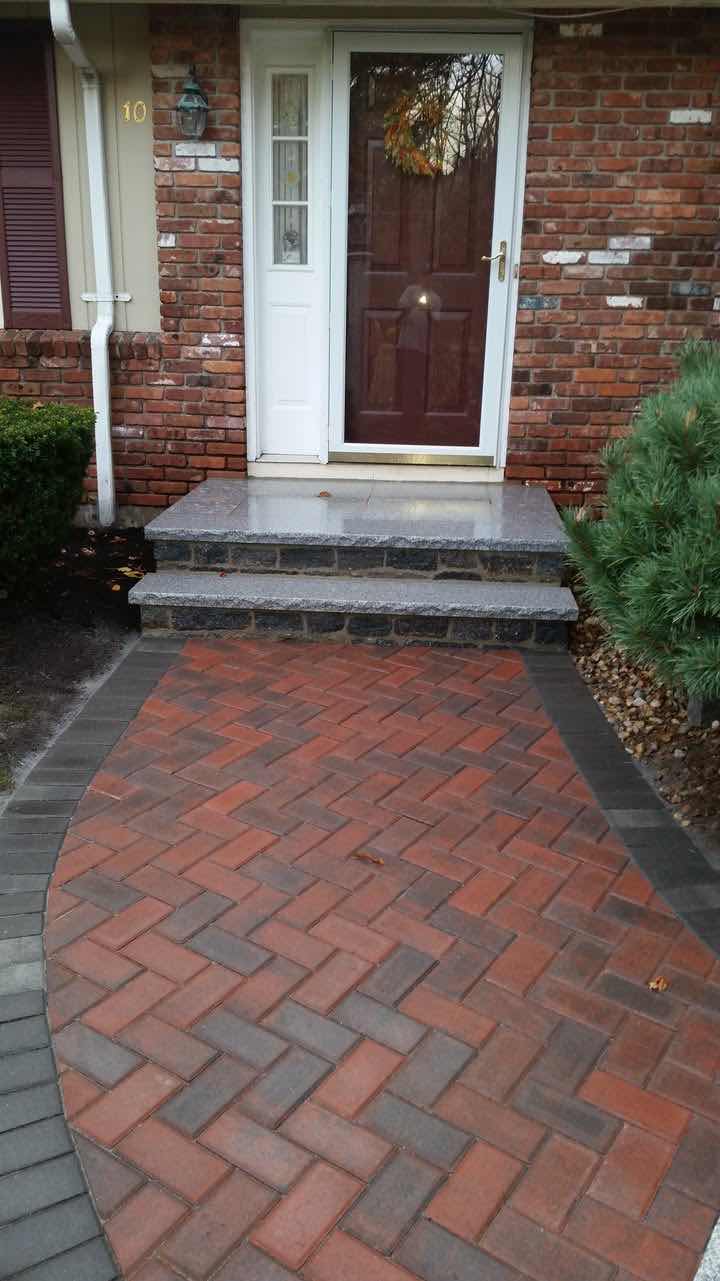 Herringbone brick walkway leading to granite-and-fieldstone entry steps, installed by Magic Tools Contracting