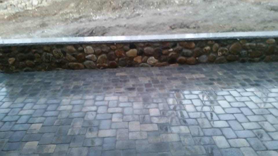 Close-up detail of a fieldstone retaining wall base along a paver patio, built by Magic Tools Contracting