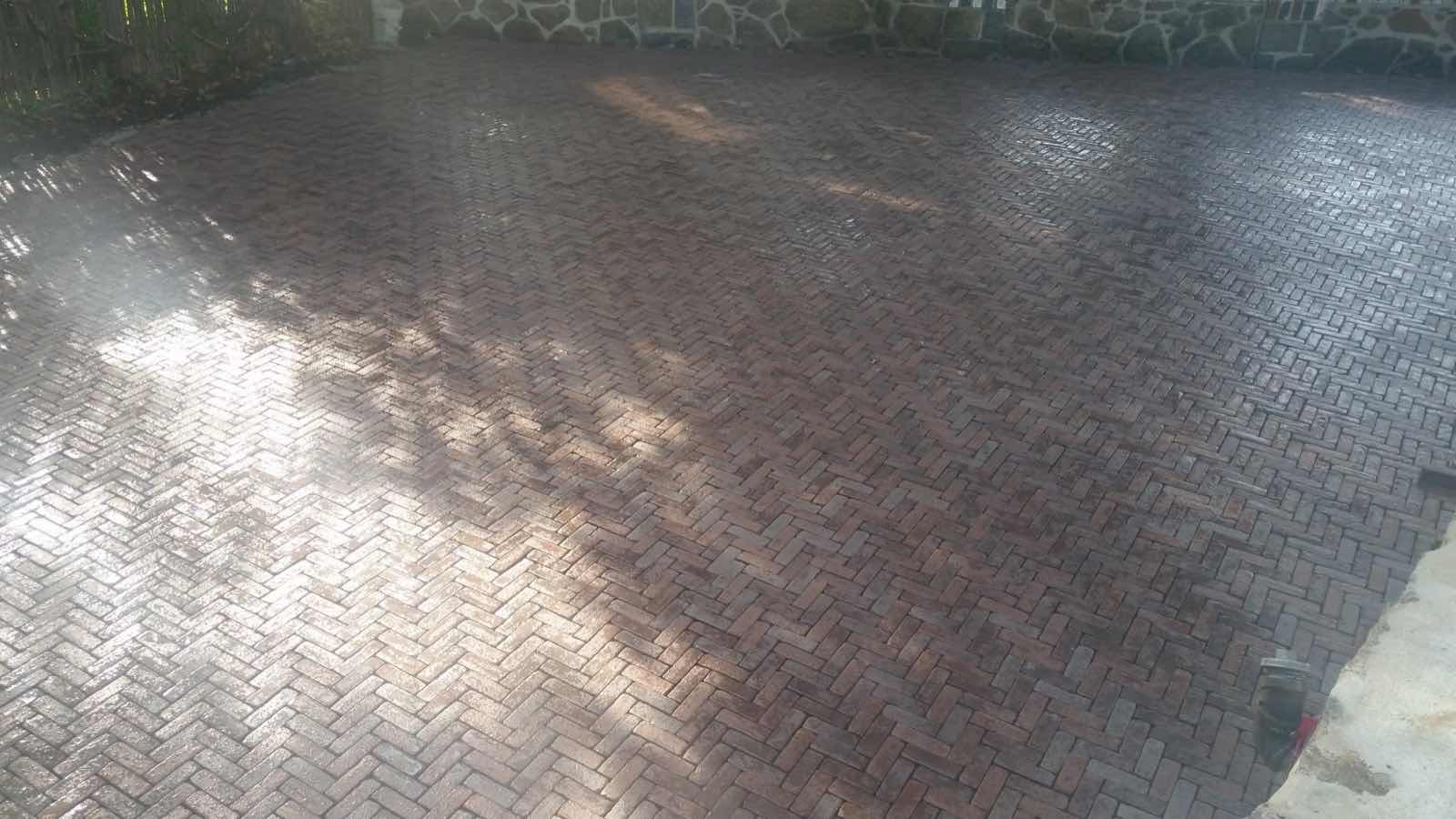 Herringbone brick patio bordered by a fieldstone wall, installed by Magic Tools Contracting