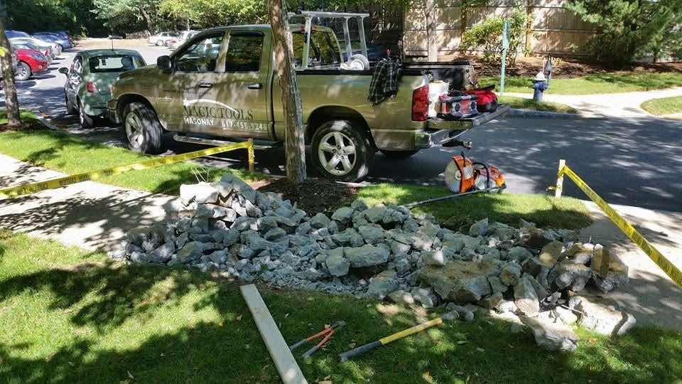 Magic Tools Masonry work truck next to a pile of demolished stone during a masonry removal project