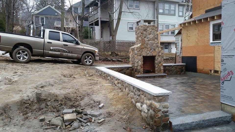 Magic Tools Masonry truck parked beside a fieldstone outdoor fireplace under construction