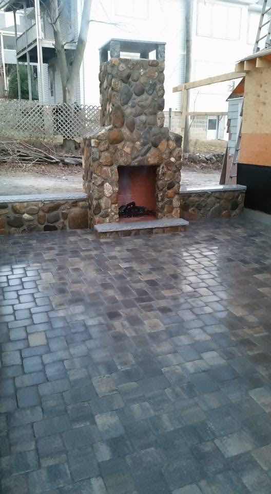 Completed fieldstone outdoor fireplace with matching paver patio built by Magic Tools Contracting