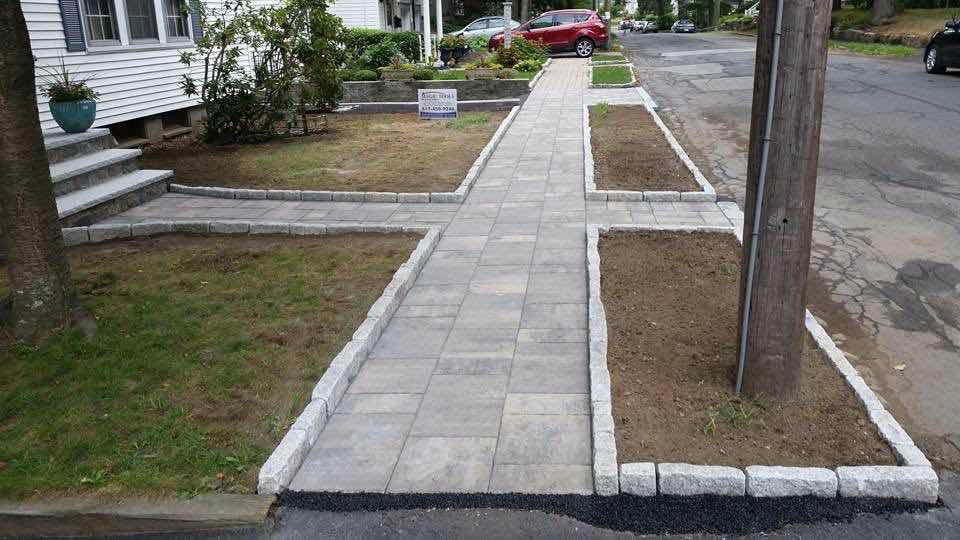 Paver walkway with granite cobblestone curbing and planting beds, installed by Magic Tools Contracting
